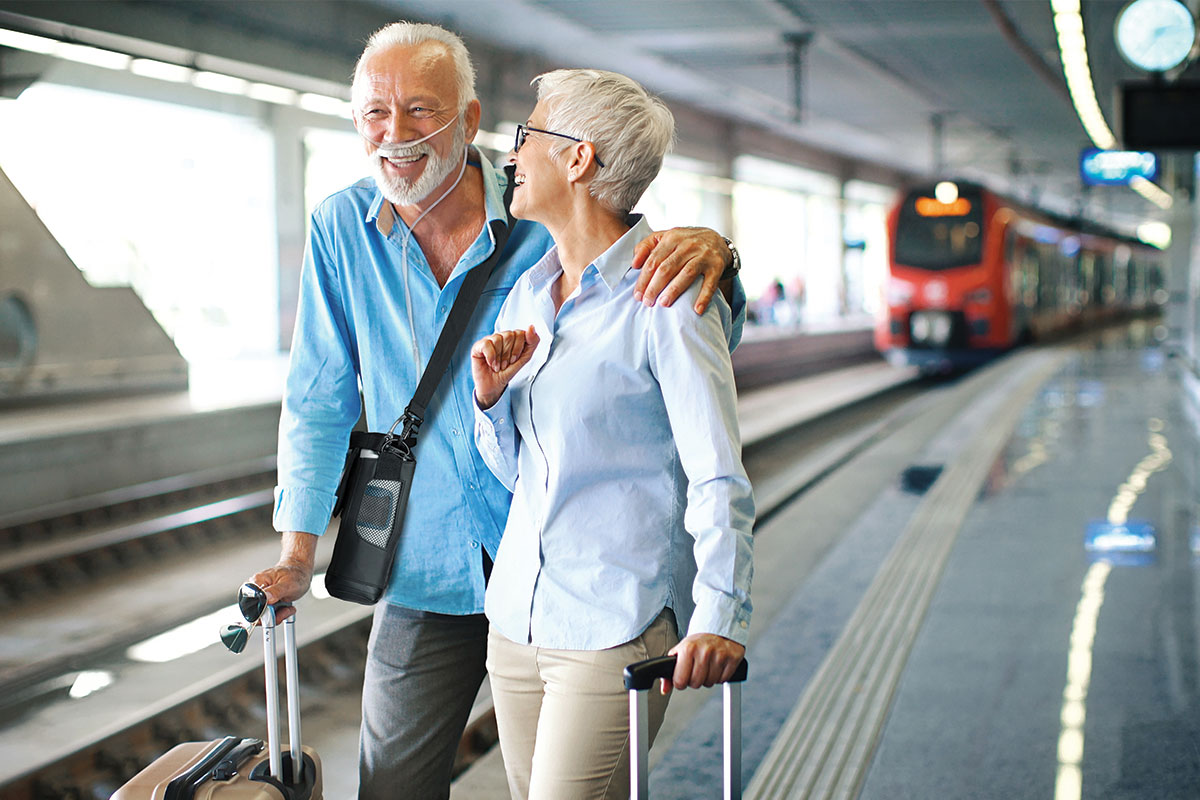 Older couple with oxygen machine preparing to board a train