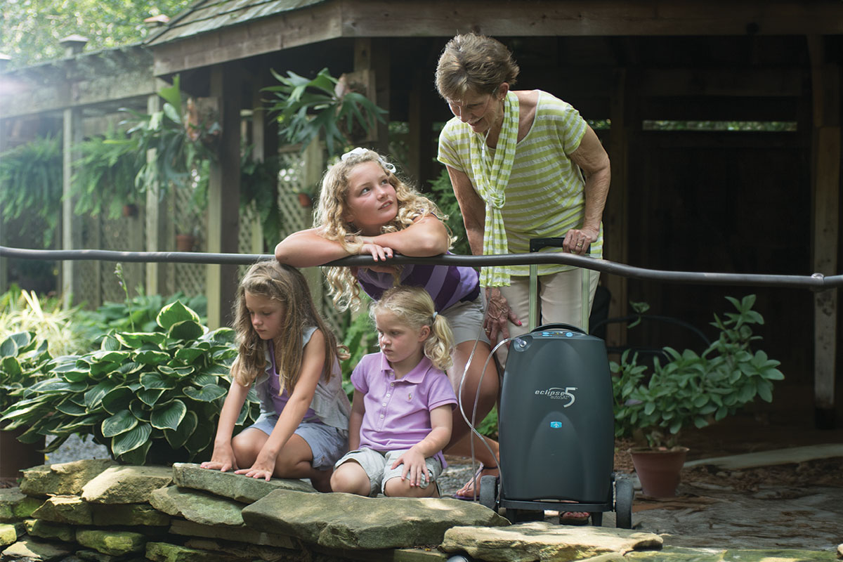 3 sisters spending time outside with their grandmother, using an oxgen machine